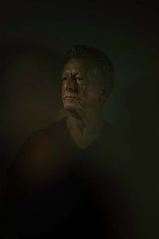 A dark and moody portrait of a man with deep wrinkles.