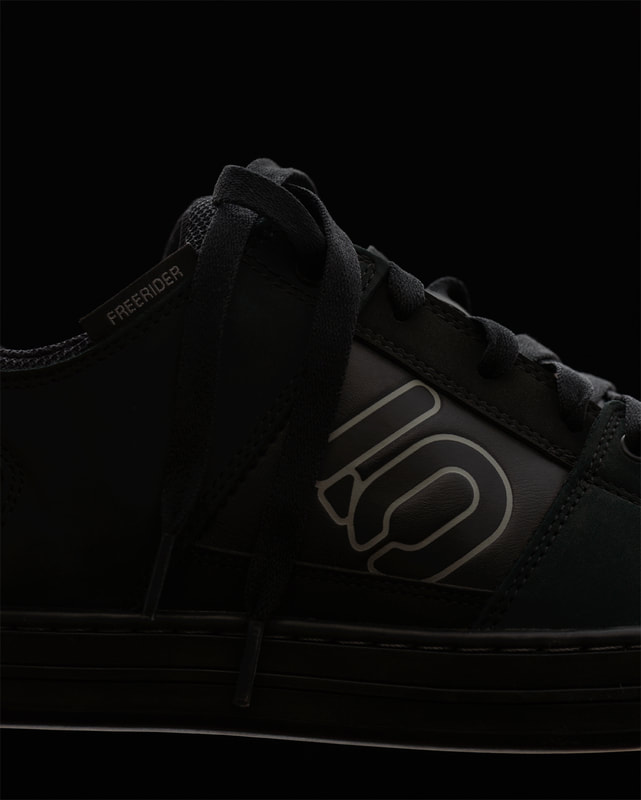 A closeup image of the centre section of a black cycling shoe. It is very selectively and subtly lit. Photographed by Mike Taylor in his studio in Peterborough Ontario Canada.