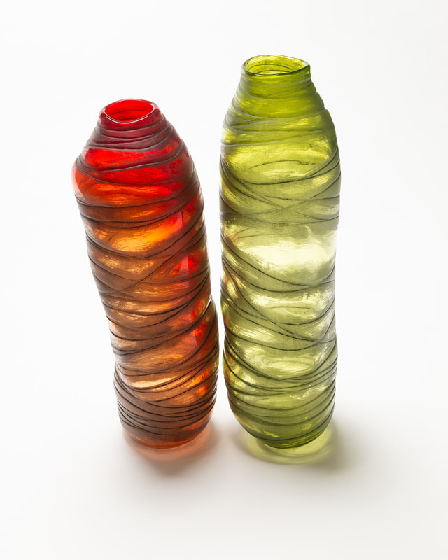 Two tall and slender objects in glass stand next to each other on a white surface. They are bright and colourful as they are strongly lit. Shot by photographer Mike Taylor in his Peterborough Ontario studio.