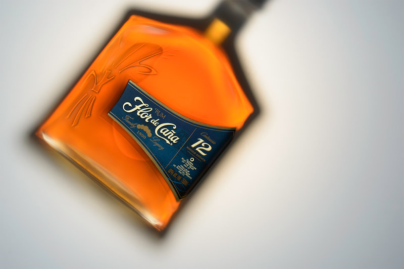 An overhead view of a bottle of Flor de Cana rum on a white surface. This studio photograph was shot in Peterborough Ontario for a speculative project.