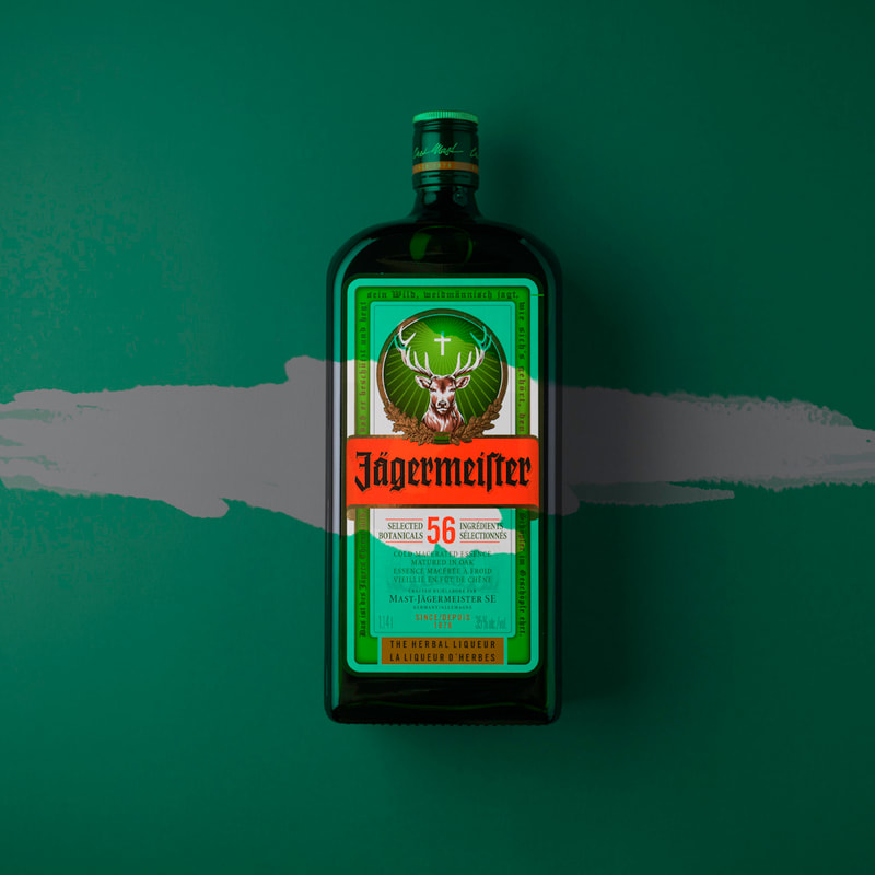 A bottle of Jagermeister rests on a green surface