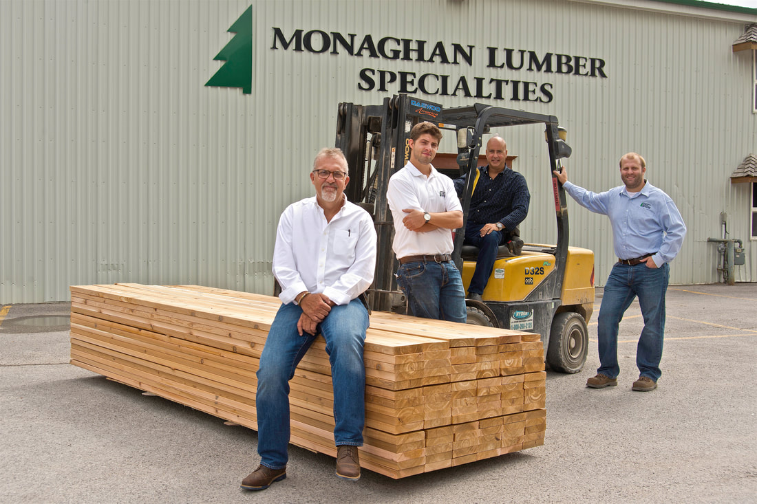 A group of men collect around and on a pallet of lumber in front of a lumber store. Shot by photographer Mike Taylor near Peterborough Ontario.