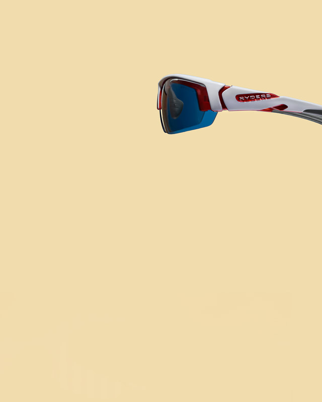 A side view image of a pair of red and white sunglasses against a sandy coloured background. An image shot by photographer Mike Taylor in his Peterborough Ontario studio.