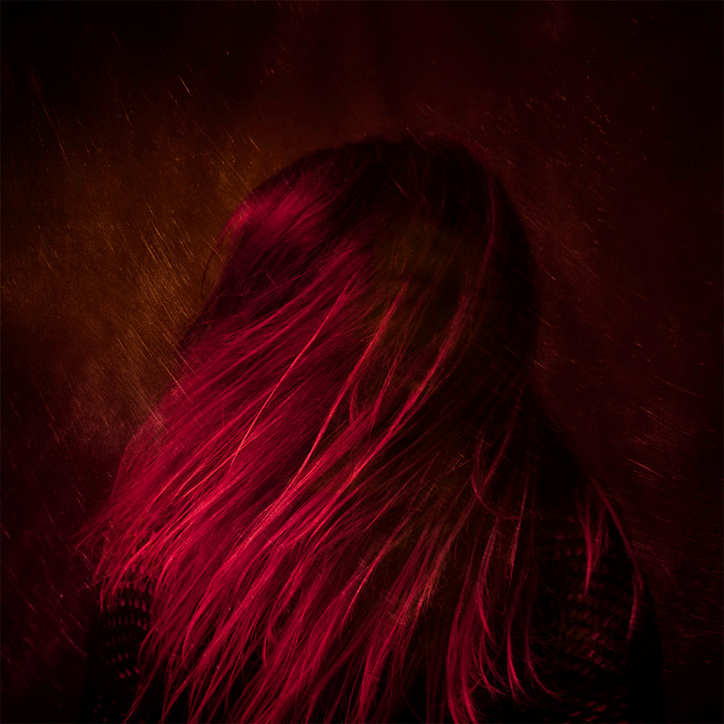 A view of the rear of a person with long hair. The image is rather reddish in colour.