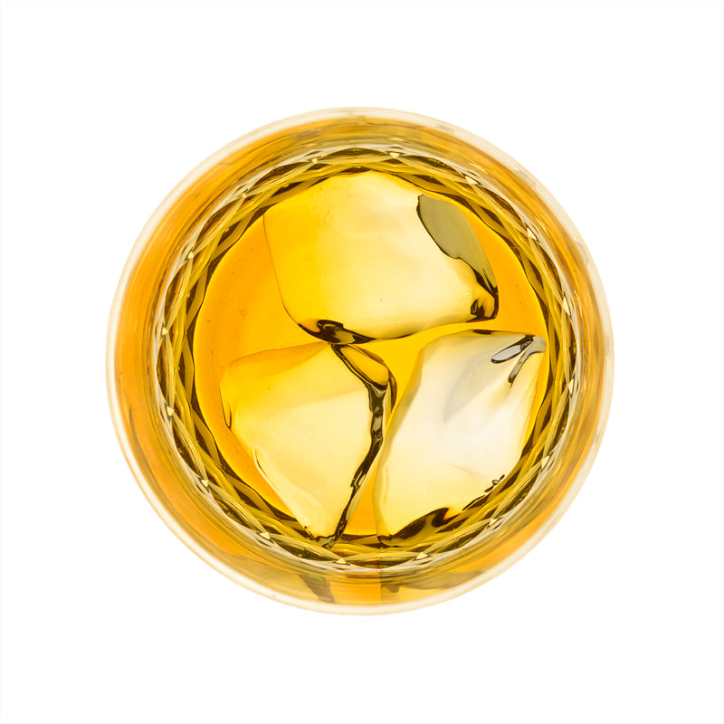 The top down view of a drinks glass with ice chunks and amber whisky within