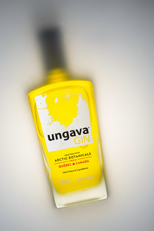 An overhead view of a bottle of yellow Ungava gin from Quebec on a white surface.