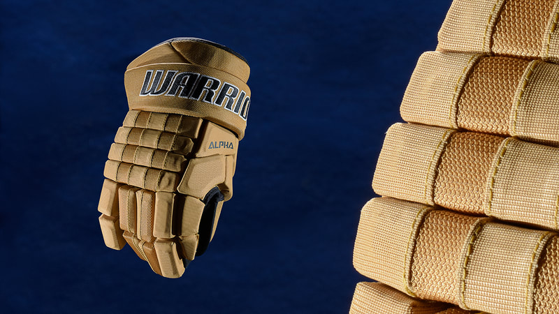 An image of a sand-coloured hockey glove against a dramatic blue background. It is dramatically lit by photographer Mike Taylor in his Peterborough Ontario studio.